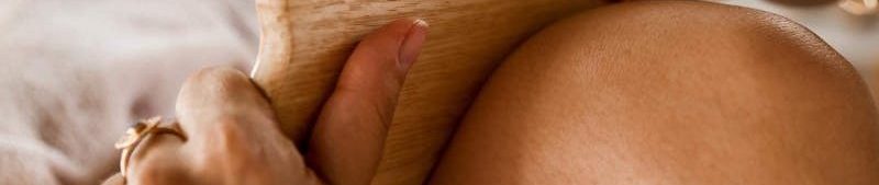 Woman Massaging a Leg with a Wooden Tool