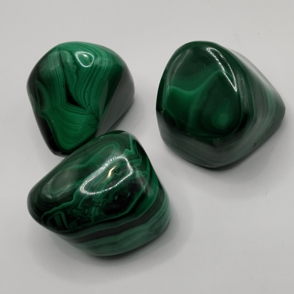Piedras pulidas de Malaquita con un intenso color verde y vetas naturales, ideales para protección, equilibrio emocional y transformación personal